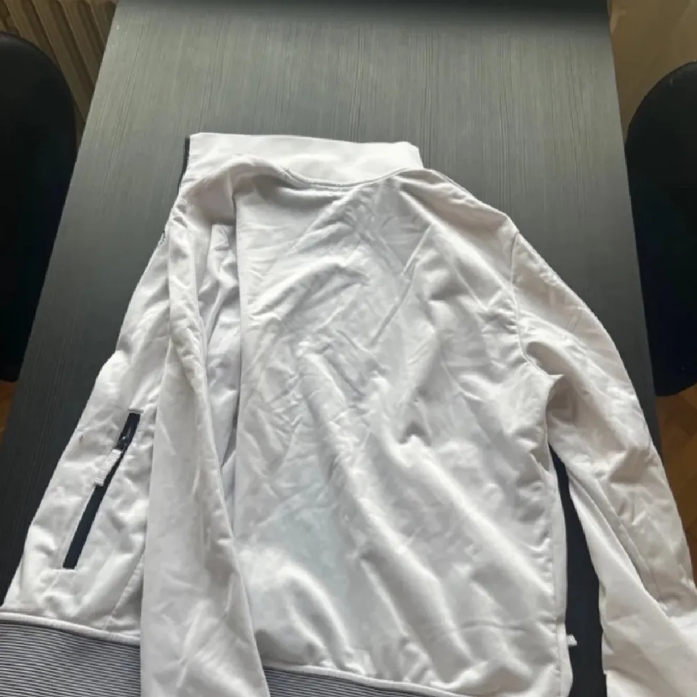Snygg vit jacka från Armani Exchange med dragkedja och stilrena detaljer. Perfekt för en sportig look. Jackan har långa ärmar och en diskret logga på bröstet.. Neuletakit & Villapaidat.