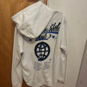 HOV1 hoodie med tryck 'Around the World Tour' - Säljer en vit HOV1 hoodie med tryck 'Around the World Tour' i svart och blått på baksidan. Framsidan har en liten blå krona. Hoodien har en stor ficka framtill och justerbar huva med dragsko. Aldrig använd Inga skavanker och säljes enbart då jag ej är så förtjust i bandet. Ny pris 600kr kan sänka priset till men inte allt för mycket och då en kvick affär.
