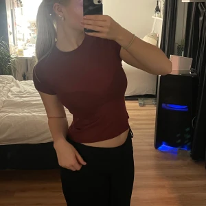 Vinröd t-shirt från Divided - Säljer en snygg vinröd t-shirt från Divided/H&M. Den är i tunt, nästan lite genomskinligt material, sitter format runt kroppen utan att vara tight, fett skön. Passar lika bra som storlek M som storlek S. 