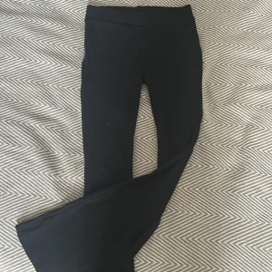 Svarta ribbade byxor - Snygga svarta ribbade byxor med hög midja och bootcut-stil. Perfekta för en stilren look och kan enkelt matchas med olika toppar. Byxorna har en bekväm passform och är tillverkade i ett stretchigt material. Från ellen new york, köpta för 300kr