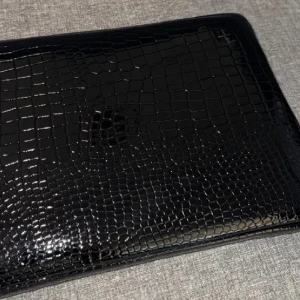 Datorväska  - Snygg och stilren svart datorväska med krokodilmönster. Perfekt för att skydda din laptop med stil. Väskan har en dragkedja för säker förvaring och en elegant finish som ger ett lyxigt intryck.