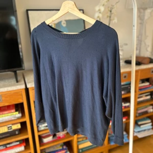 Mörkblå tröja med knytning bak - Säljer en stilren mörkblå tröja från Bondelid med knytning i nacken. Tröjan har långa ärmar och en ribbad kant vid halsen. Perfekt basic topp.