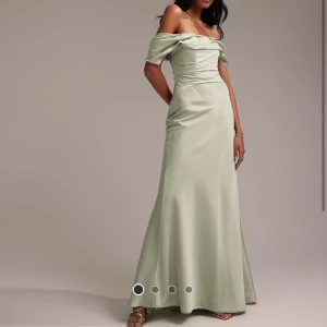 Ljusgrön axelbandslös långklänning - Säljer en elegant ljusgrön långklänning med offshoulder-design och draperad överdel. ALDRIG använd, med prislapp på. Klänningen har figurnära passform upptill och faller snyggt ner mot golvet. Perfekt för bal eller fest. Materialet har en lätt glansig yta som ger en lyxig känsla.