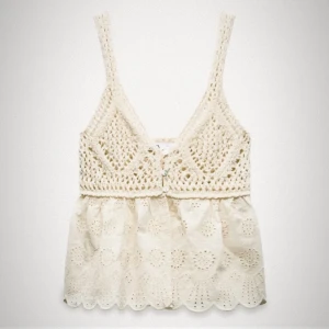 Vit spets-croppad linnetopp - Superfin vit linnetopp med virkade detaljer upptill och spetsmönster nertill. Croppad modell med breda axelband och knäppning framtill. Perfekt för sommardagar och festivaler.