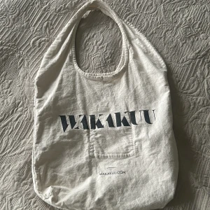 Vit tygpåse från Wakakuu - Säljer en vit tygpåse från Wakakuu med tryckt logga på framsidan. 