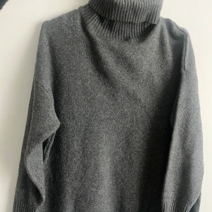 Grå polo klänning från Nelly - Mysig stickad polo klänning från Nelly med lång ärm och hög, ribbad krage. Perfekt för kyliga dagar. Tröjan kan användas både som klänning och tunika!!! Nyskick 🩶