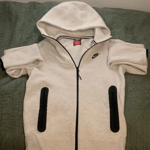 Vit zip-hoodie från Nike med svarta detaljer - Säljer en vit hoodie från Nike med dragkedja och svarta detaljer vid fickor och logga. Har använt den en gång bara höra av sig kvalitet 10/10! 