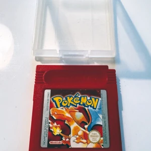 Pokémon Red till Game Boy - Säljer ett klassiskt Pokémon Red-spel till Game Boy. Kassetten är röd och har en etikett med Charizard på framsidan. Medföljer gör även ett genomskinligt plastfodral för förvaring. Perfekt för samlare eller retrospelare!