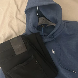 Ralph lauren hoodie och replay jeans - Säljer en blå hoodie från Polo Ralph Lauren med klassisk vit logga broderad på bröstet. Tröjan har huva med dragsko och är tillverkad i mjukt material. Perfekt för en avslappnad stil.