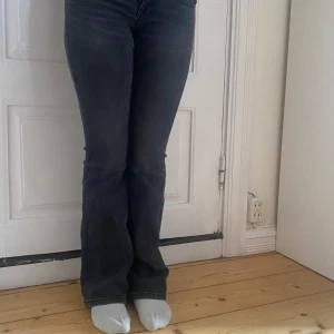 Mörkblå bootcut jeans från Gina Tricot - Säljer ett par mörkgrå jeans från Gina Tricot med bootcut-modell. Jeansen har klassisk femficksdesign, normal passform och är tillverkade i ett stretchigt denimtyg. Perfekta för dig som gillar en tidlös look med lite utsvängda ben.