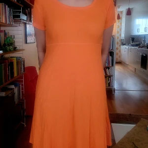 Orange ribbad klänning från Kosinski - Säljer en orange ribbad sommarklänning från Kosinski i storlek M. Klänningen har korta ärmar, rund halsringning och en lätt utställd kjol. Perfekt för dig som gillar färg och enkel stil.