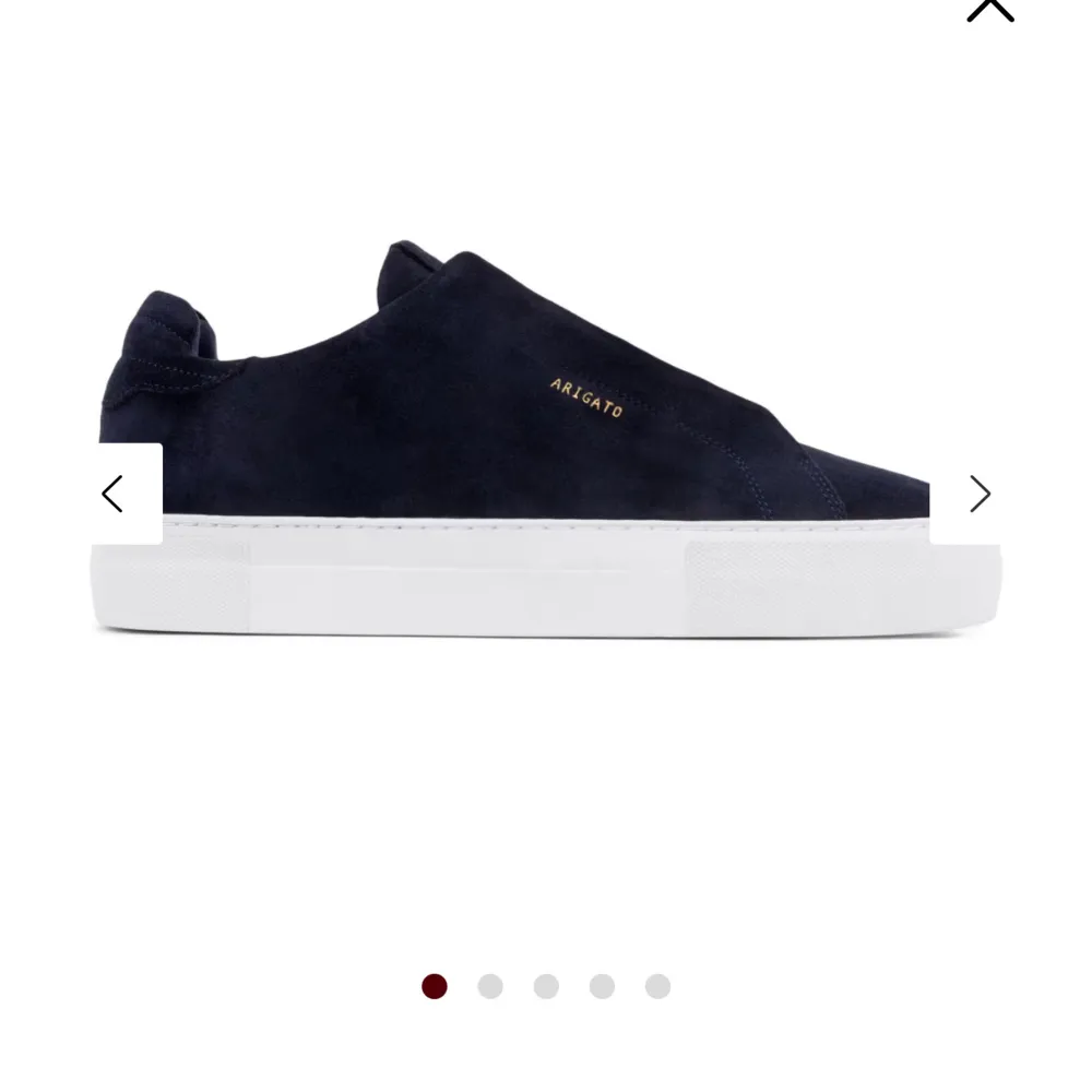 Stilrena svarta sneakers från Axel Arigato i mocka med vit platt sula. Diskret guldfärgad logotyp på sidan. Perfekta för en clean och modern look.. Kengät.