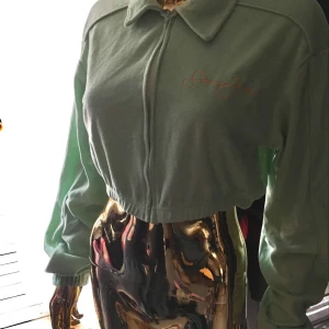 Mintgrön croppad zip tröja från Missguided - Säljer en mintgrön croppad jacka från Missguided med dragkedja framtill och broderad text på bröstet. Oanvänd med lapp kvar 