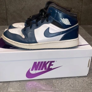 Nike Air Jordans Mid Navy/White - Säljer ett par Nike Air Jordans Mid i marinblått och vitt. Skorna har klassisk hög siluett, vit bas med mörkblå overlays och svart snörning. Oanvänd helt ny. 