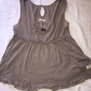 Beige babydoll topp från Odd Molly - Supersöt beige babydoll topp från Odd Molly med en liten rosett framtill och fjäril på ryggen. Den har en defekt som man ser i bild 3.
