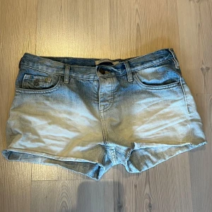 Ljusblå jeansshorts från Maison Scotch - Säljer ett par ljusblå jeansshorts från Maison Scotch. Shortsen har normal passform och är perfekta för varma dagar. Snygg Maison Scotch-lapp bak i midjan. Storlek w27 passar som s/m.