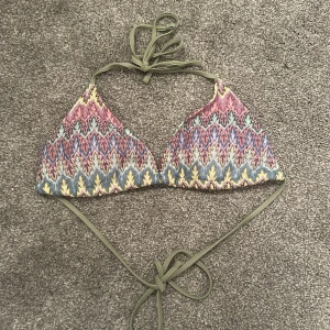 Flerfärgad bikiniöverdel med knyt - Säljer en snygg bikiniöverdel i trekantsmodell med knyt i nacken och ryggen. Mönstret är färgglatt i rosa, blått, gult och grönt med en bohemisk känsla. Perfekt för stranden eller poolen!