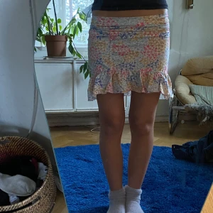 Blommig volangkjol i pastellfärger - Säljer denna supersöta kjolen med blommor på i olika somriga färger. Kjolen är från ginatricot i storlek XS. 
