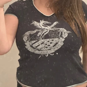 Svart t-shirt y2k baby tee från Tommy Hilfiger - Svart gullig baby tee t-shirt från Tommy Hilfiger med vitt emblemtryck framtill och kontrastsömmar vid hals, ärmslut och nederkant. Modellen är croppad och har korta ärmar samt rund halsringning. Använd fåtal gånger💕