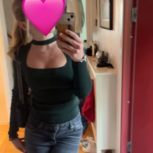 Mörkgrön långärmad topp med choker-detalj från Zara - Säljer en mörkgrön långärmad topp från Zara med unik choker-detalj och fyrkantig urringning. Toppen är figurnära och har en stilren, minimalistisk look som passar perfekt till jeans eller kjol.