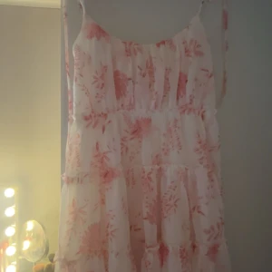 Sommarklänning  - så söt kort vit klänning med rosa blommor på💕 den är köpt förra året men är endast testat💕 lappen står inte kvar och minns inte märket💕tror klänningen är i storlek m men passar s bra också💕 skriv gärna vid frågor och prisförslag 💕💕