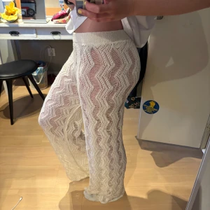Vita virkade byxor med vågigt mönster - Säljer ett par vita virkade byxor med vågigt mönster. Byxorna är genomskinliga och har en loose passform med resår i midjan. Perfekta att dra över badkläder eller för en chill sommarlook.