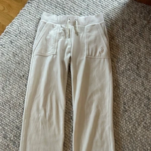 Vita mjukisbyxor från Juicy Couture - Säljer ett par vita mjukisbyxor från Juicy Couture i storlek XS. Metallen på snörena har lossnat men annars i väldigt bra skick och väl omhändertagna❤️nypris är 1000