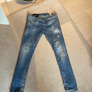 Blå slim jeans från Dondup - Säljer ett par blå slim jeans från Dondup med slitningar och distressed detaljer. Jeansen har klassisk femficksdesign, dragkedjegylf och låg midja. Perfekta för dig som gillar en smal passform och trendig look.
