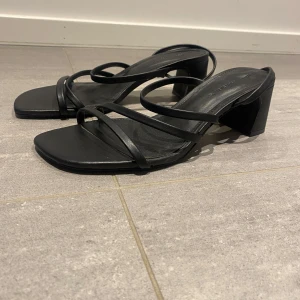 Svarta klackar från Pull & Bear - Säljer ett par stilrena svarta klackar med fyrkantig tå och blockklack. Skorna har flera tunna remmar över foten och där bak. De är i storlek 37. Köpte de själv från en tjej här på Plick men de var för stora så säljer därför de här. 