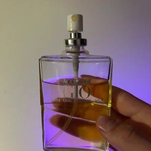 Acqua di Giò pour Homme parfym - Klassisk Acqua di Giò pour Homme parfym från Giorgio Armani i en transparent glasflaska med silvrig spraykork. Flaskan rymmer 100 ml och har en stilren, rektangulär form med tydlig logotyp på framsidan.