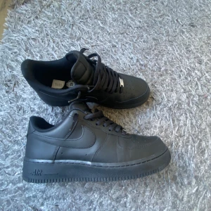 Svarta Nike Air Force 1 - Säljer ett par helsvarta Nike Air Force 1. Knappast använda, mycket bra skick. Nypris 1500kr. Kommer med box ej kvitto.