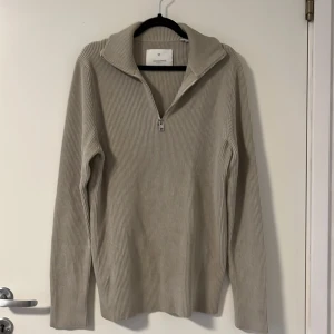Beige ribbad stickad tröja med dragkedja - Säljer en beige ribbad stickad tröja från Jack&Jones med krage och dragkedja framtill. Enkel och stilren design som passar till mycket.