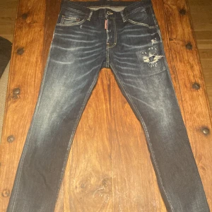  Dsquared2 jeans ÄKTA - Säljer ett par mörkblå jeans från Dsquared2 med slitningar och detaljerade sömmar. Jeansen har klassisk femficksdesign, gylf med dragkedja och Dsquared2-logga på etiketten. Snygg tvätt och slim passform. Självklart äkta orderbekräftelsen finns! Helt perfekt i skicket inget fel på dem alla