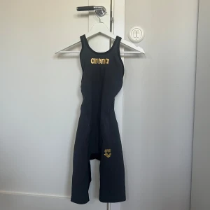 Arena tävlingsbaddräkt - Tävlingsbaddräkt från arena. Använd men fortfarande i bra skick. Baddräkten är i storlek UK 26 (se bild). Säljes då jag slutat simma. Pris ligger på 1000 kronor. Köparen står för porto.