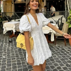 Vit klänning med puffärmar - Säljer en söt vit klänning med puffiga kortärmar och v-ringning. Klänningen har ett fint broderat mönster  Perfekt för studenten 