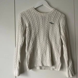 Vit stickad tröja från Seaside - Säljer en vit stickad tröja storlek XS. Tröjan har ett klassiskt kabelstickat mönster, rund halsringning och långa ärmar. Perfekt för lager-på-lager och enkel att matcha med olika outfits.