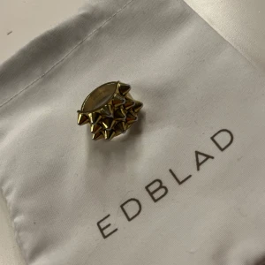 Guldfärgad ring med nitar från Edblad - Cool ring från Edblad i guldfärg med flera spetsiga nitar runt om. Perfekt statement-smycke för dig som vill sticka ut. Kommer i originalpåse från Edblad, i storlek 16,80💞