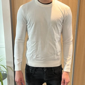Vit långärmad tröja från HM i bomull - Säljer en stilren vit långärmad tröja i bomull. Tröjan har rund halsringning och en klassisk passform som sitter snyggt på kroppen. Perfekt att matcha med jeans eller chinos för en clean look.
