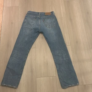 Levi's 501 jeans blå - Klassiska blå Levi's 501 jeans med raka ben och femficksmodell. Byxorna har knappgylf och läderpatch bak i midjan. Perfekta för en avslappnad och tidlös stil. W30/ L34
