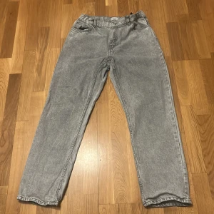 Grå jeans från Grunt - Säljer ett par riktigt feta gråa jeans från Grunt med raka ben och klassisk femficksdesign. Jeansen har normal passform, knapp och dragkedja i gylfen samt bälteshällor. Perfekta till en skön och relaxed outfit.