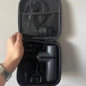 Massagepistol i svart fodral - Säljer en massagepistol + laddare i svart. Kommer i ett hårt svart fodral med dragkedja och handtag. Inkluderar fyra olika massagehuvuden och laddkabel. Perfekt för återhämtning efter träning eller för att lindra muskelspänningar.