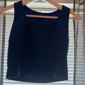 Mörkblå croppad linnetopp - Säljer en enkel och stilren mörkblå croppad linnetopp med rund halsringning. Perfekt att matcha med jeans eller kjol för en avslappnad look.