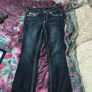 Mörkblå jeans med vita sömmar och broderade bakfickor - Säljer ett par mörkblå jeans med tydliga vita kontrastsömmar och snygga broderier på bakfickorna. Klassisk femficksmodell med raka ben och normal passform. Perfekta för dig som vill ha jeans med lite extra detaljer.