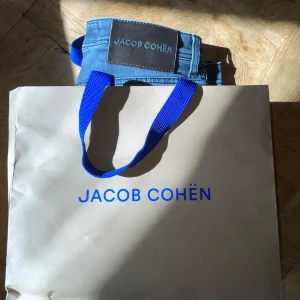Gråa jeans från Jacob Cohën - Säljer ett par klassiska grå jeans från Jacob Cohën i modellen Bard. Jeansen har fem fickor, silverfärgade knappar och en patch med logga bak i midjan. Använda ett fåtal gånger. Kasse följer inte med. 