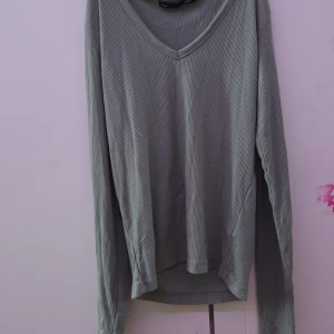 Grön ribbad tröja från H&M - Säljer en stilren grön ribbad tröja. Tröjan har en v-ringad hals och långa ärmar, perfekt för en avslappnad look. Passar bra till både jeans och kjol. Perfekt för vår och höst!