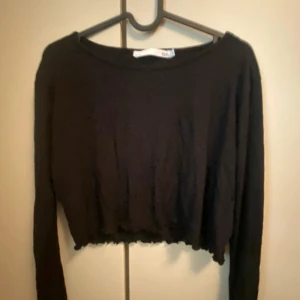 Svart croppad tröja från 157 - Säljer en svart croppad tröja från 157. Tröjan har långa ärmar och en enkel design som passar perfekt till vardags. Den är gjord i ett mjukt material som känns skönt mot huden.