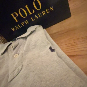  pikétröja polo Ralph Lauren - Säljer en stilren grå pikétröja från Ralph Lauren med klassisk krage och knappar framtill. Tröjan har en broderad logotyp på bröstet. Perfekt för en avslappnad men ändå elegant look. Säljer lågt för att den säljs inte pris kan diskuteras 