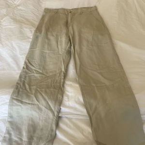 Hope wind trousers - Snygga beige byxor från Hope i modellen Wind Trouser. Tillverkade av en mjuk blandning av lyocell och linne, vilket ger en skön och luftig känsla. Byxorna har en loose passform och är perfekta för en avslappnad stil. 