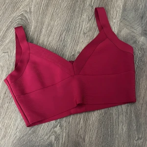 Vinröd korsettopp - Snygg vinröd korsettopp med breda axelband och dragkedja i ryggen. Perfekt för en stilren look. Toppen har en elegant och figurnära passform.