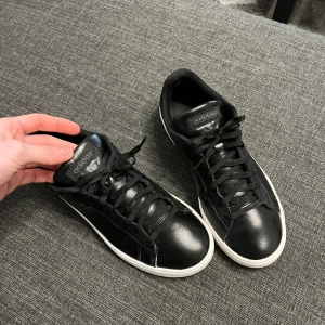 Svarta sneakers, Adidas - Snygga svarta sneakers från Adidas med klassisk design och vit sula. Skorna har snörning och är tillverkade i syntetmaterial, vilket ger en stilren look. Perfekta för en avslappnad stil. Nypris ca1000kr. Priset kan diskuteras vid snabb köp😊